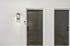 Elegant apartment entrance with modern dark doors featuring sleek smart locks, accented by a stylish wall lamp.