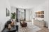 Bright and modern living room with chic d&eacute;cor, featuring a comfortable grey sofa, stylish wall art, and a large window flooding the space with natural light.