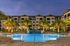 Elegant apartment complex with illuminated palm trees surrounding a luxurious resort-style pool at dusk.