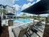 Luxurious apartment complex featuring a sparkling outdoor pool, stylish lounge chairs, and elegant landscaping under a sunny sky.