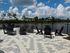 Elegant outdoor patio with stylish seating and stunning waterfront views, perfect for relaxing under the clear blue sky.