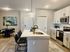 Modern kitchen with sleek white cabinets, island seating, and inviting dining area with contemporary art.