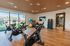 Modern fitness room with stationary bikes, free weights, and large windows offering natural light and outdoor views.