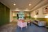 Inviting apartment lobby with modern green accents, cozy seating area, abstract art, and warm lighting.