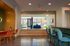 Inviting apartment lobby with modern seating, ambient lighting, and vibrant wall art leading to a sunny outdoor space.