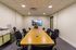 Sleek modern conference room with a stylish wooden table, comfortable chairs, and a large TV screen, ideal for productive meetings.