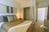 Inviting bedroom with modern decor, featuring a cozy bed, warm lighting, and spacious open closet.