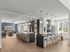 Modern open-concept kitchen and living area with sleek countertops, elegant pendant lighting, and large windows providing natural light.