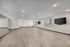 Spacious, well-lit room with sleek wood flooring and large mirrored wall, perfect for exercise or dance studio.