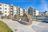Modern apartment complex with lush green lawns, chic wicker seating, and inviting outdoor patio spaces basking in sunlight.