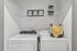 Sleek laundry area with modern washer and dryer, accented by decorative shelving and a stylish storage basket.