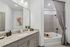 Modern bathroom with elegant granite countertops, stylish vanity, and a relaxing bathtub with chic patterned curtain.