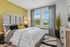 Inviting bedroom with a luxurious bed, accent pillows, and serene natural light streaming through large windows.