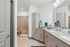 Modern bathroom with sleek granite countertops, double sinks, and a spacious glass-enclosed shower, ideal for a luxurious apartment setting.