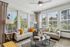 Bright and inviting living room with large windows, cozy couches, vibrant cushions, and modern decor, perfect for relaxation.