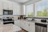 Bright and modern kitchen with sleek white cabinets, granite countertops, and stainless steel appliances, flooded with natural light.