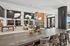 Luxurious open-concept living area with modern decor, natural light, and elegant hanging lights. Features a cozy seating area, stylish pool table, and a spacious countertop with comfortable seating.