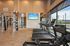 Luxurious apartment gym with state-of-the-art fitness equipment, sleek treadmills, rowing machine, and vibrant outdoor view.