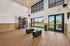 Modern fitness room featuring high ceilings, stylish wood flooring, and state-of-the-art exercise equipment with a view of a lush outdoor garden.