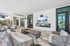Elegant outdoor lounge area featuring modern seating, sleek tables, and a large flat-screen TV, perfect for relaxation and entertainment.