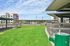 Inviting outdoor space featuring well-maintained green grass, modern seating, and sleek architectural elements under a bright blue sky.