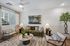 Inviting living room with modern decor, featuring a comfy green sofa, elegant armchairs, and stylish coffee table in a bright, naturally lit space.