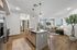 Modern open-concept kitchen and living area with sleek appliances, natural wood flooring, and bright lighting.
