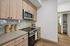 Contemporary kitchen with elegant wood cabinetry, sleek countertops, modern stainless steel appliances, and decorative pasta jars.
