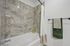 Modern bathroom showcasing elegant marble wall tiles, inviting white bathtub, and chic towel set, offering a luxurious spa-like atmosphere.
