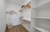Spacious walk-in closet with elegant wooden hangers, open shelving, and sleek laminate flooring.