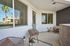 Inviting modern balcony with cozy seating, potted plants, and a stylish outdoor rug, perfect for relaxation with scenic palm tree views.