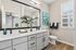 Modern bathroom with sleek white cabinetry, elegant countertop, and a large mirror reflecting natural light.