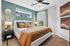 Elegant bedroom with stylish decor, featuring a cozy bed, modern ceiling fan, and abundant natural light from dual windows.
