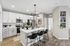 Modern kitchen with sleek white cabinetry, stainless steel appliances, chic pendant lighting, and a spacious breakfast bar with black stools.