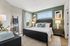 Elegant bedroom with a cozy double bed, stylish decor, and ample natural light from large windows. Modern accents and soft color palette create a serene atmosphere.