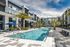 Luxurious apartment complex with a stunning resort-style pool, surrounded by palm trees and elegant lounge chairs, perfect for relaxation.