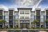 Contemporary apartment building with a sleek facade, modern architecture, and inviting entrance set under a vibrant blue sky.