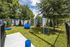 Inviting pet-friendly park with agility equipment, lush grass, and mature trees for shaded relaxation.
