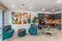 Inviting apartment lounge with vibrant abstract art, modern seating, and chic kitchenette.