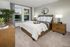 Elegant bedroom featuring a plush bed with a wooden frame, soft gray walls, and chic decor with natural lighting.