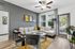 Chic living room with modern gray sectional, warm yellow accents, and stylish artwork, bathed in natural light from large windows.