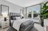 Elegant bedroom with modern decor, featuring a plush gray bed, stylish lamps, and large windows offering abundant natural light.