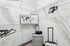 Elegant closet space with wire shelving, minimalist black hangers, and stylish travel-themed decor alongside modern silver luggage.