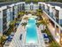 Luxurious apartment complex with a central sparkling pool, surrounded by modern architecture and lush palm trees, offering an upscale living experience.