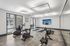 Modern fitness room with sleek lighting, exercise bikes, and a rowing machine, featuring a large wall mirror for enhanced workout experience.