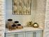 Charming kitchen nook with decorative gold metal wall art, modern cabinetry, and stylish glass jars.