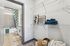 Modern apartment hallway leading to a stylish bathroom with a tub, chic tile design, and vibrant floral shower curtain; artfully decorated with elegant shelving and cozy linens.
