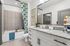 Elegant bathroom featuring a modern granite countertop, stylish cabinetry, and a cozy bathtub with a vibrant floral curtain.