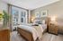 Inviting bedroom with a stylish design featuring a cozy bed, elegant decor, and abundant natural light through large windows.