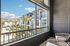 Inviting balcony view showcasing a modern apartment complex with lush palm trees and vibrant green landscaping under a clear blue sky.